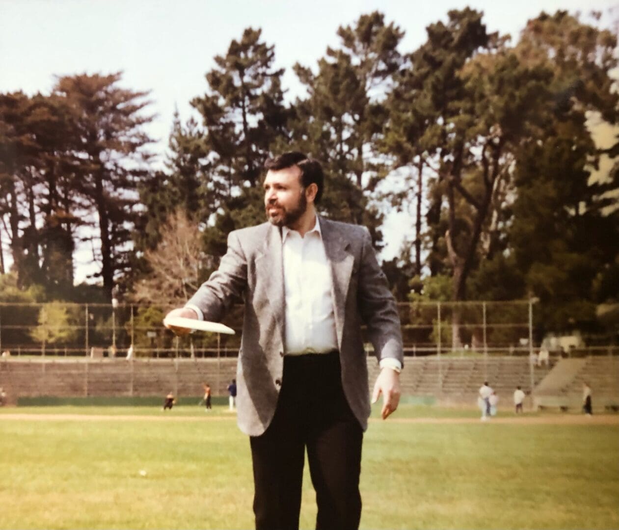A man in a suit stands on the grass.